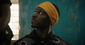 Movie still from “The Day Shall Come” (2019), directed by Christopher Morris – A man with a yellow head band looking up; Close Up shot, Low angle