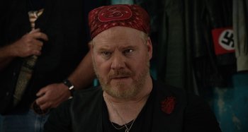 Movie still from “The Day Shall Come” (2019), directed by Christopher Morris – A person with a beard wearing a hat; Close Up shot, Over the shoulder angle