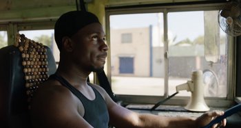 Movie still from “The Day Shall Come” (2019), directed by Christopher Morris – A man sitting in a vehicle looking out the window; Close Up shot, Low angle