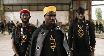 Movie still from “The Day Shall Come” (2019), directed by Christopher Morris – A group of men standing next to each other; Medium shot, Over the shoulder angle