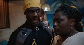 Movie still from “The Day Shall Come” (2019), directed by Christopher Morris – A man and a woman posing for a picture; Medium shot, Over the shoulder angle