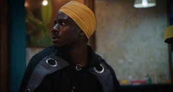 Movie still from “The Day Shall Come” (2019), directed by Christopher Morris – A man wearing a yellow hat and a black jacket; Close Up shot, Low angle