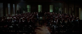 Movie still from “The Day of the Dolphin” (1973), directed by Mike Nichols – A large group of people sitting in a room at night; Extreme Wide shot, High angle
