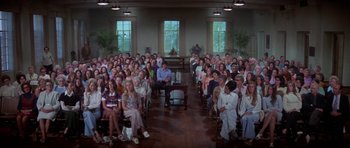 Movie still from “The Day of the Dolphin” (1973), directed by Mike Nichols – A large group of people sitting in a room; Wide shot, High angle