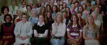 Movie still from “The Day of the Dolphin” (1973), directed by Mike Nichols – A large group of people sitting in a room; Medium shot, High angle