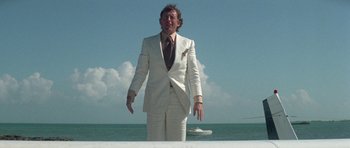 Movie still from “The Day of the Dolphin” (1973), directed by Mike Nichols – A man in a white suit standing in front of a body of water; Medium shot, Low angle