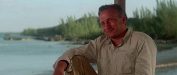 Movie still from “The Day of the Dolphin” (1973), directed by Mike Nichols – A man sitting on a boat in the middle of a river; Close Up shot, Low angle