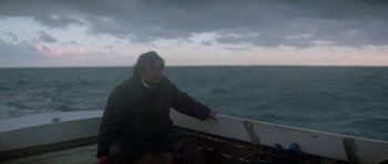 Movie still from “The Day of the Dolphin” (1973), directed by Mike Nichols – A man sitting on the back of a boat in the ocean; Medium shot, High angle