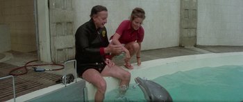 Movie still from “The Day of the Dolphin” (1973), directed by Mike Nichols – Two people in a pool with a fake dolphin; Medium shot, High angle