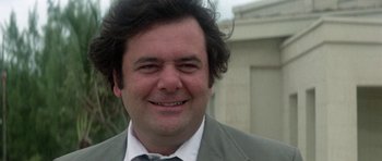 Movie still from “The Day of the Dolphin” (1973), directed by Mike Nichols – A person wearing a suit and smiling; Close Up shot, Low angle