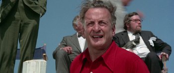 Movie still from “The Day of the Dolphin” (1973), directed by Mike Nichols – An older man in a red shirt is smiling; Close Up shot, Low angle