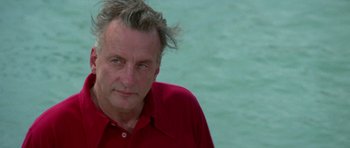 Movie still from “The Day of the Dolphin” (1973), directed by Mike Nichols – A person wearing a red shirt near a body of water; Close Up shot, Low angle