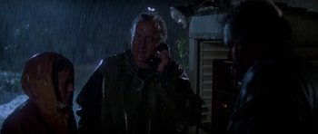 Movie still from “The Day of the Dolphin” (1973), directed by Mike Nichols – A man talking on a cell phone while standing in the rain; Close Up shot, Low angle