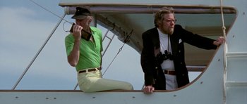 Movie still from “The Day of the Dolphin” (1973), directed by Mike Nichols – Two men are sitting on a plane looking out the window; Medium shot, Low angle