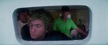 Movie still from “The Day of the Dolphin” (1973), directed by Mike Nichols – A man sitting next to another man on a boat; Close Up shot, Over the shoulder angle