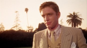 Movie still from “The Day of the Locust” (1975), directed by John Schlesinger – A man in a suit and tie standing in front of palm trees; Close Up shot, Low angle