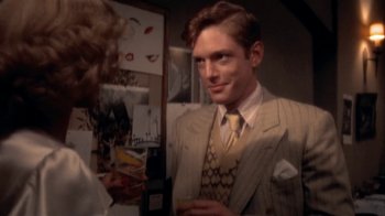 Movie still from “The Day of the Locust” (1975), directed by John Schlesinger – A man in a suit and tie looking at a woman in a suit; Close Up shot, High angle