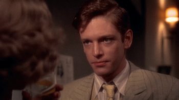 Movie still from “The Day of the Locust” (1975), directed by John Schlesinger – A man in a suit holding a glass of whiskey; Close Up shot, Over the shoulder angle