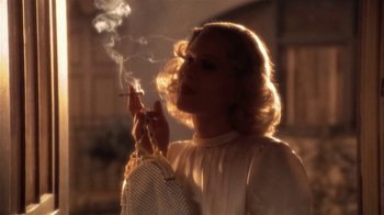 Movie still from “The Day of the Locust” (1975), directed by John Schlesinger – A woman smoking a cigarette while holding a purse; Close Up shot, Low angle