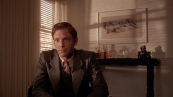 Movie still from “The Day of the Locust” (1975), directed by John Schlesinger – A man in a suit sitting in front of a window; Medium shot, Over the shoulder angle