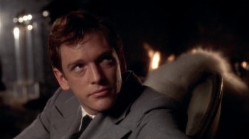 Movie still from “The Day of the Locust” (1975), directed by John Schlesinger – A man in a suit and tie sitting in front of a fireplace; Close Up shot, Over the shoulder angle