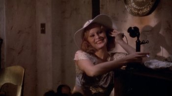 Movie still from “The Day of the Locust” (1975), directed by John Schlesinger – A woman wearing a white cowboy hat is smiling for the camera; Medium shot, Low angle