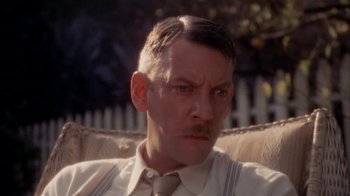 Movie still from “The Day of the Locust” (1975), directed by John Schlesinger – A person sitting on a couch wearing a tie; Close Up shot, High angle