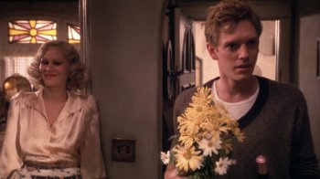 Movie still from “The Day of the Locust” (1975), directed by John Schlesinger – A man holding a bouquet of flowers in front of a woman; Medium shot, Over the shoulder angle