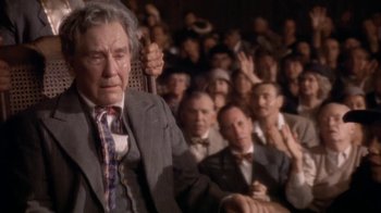 Movie still from “The Day of the Locust” (1975), directed by John Schlesinger – An old man in a suit holding a cane in front of an audience; Medium shot, High angle