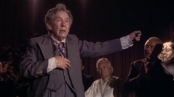 Movie still from “The Day of the Locust” (1975), directed by John Schlesinger – An older man wearing a suit and tie; Medium shot, Over the shoulder angle