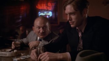 Movie still from “The Day of the Locust” (1975), directed by John Schlesinger – Two men sitting at a table in front of a neon sign; Medium shot, Over the shoulder angle