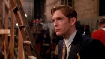 Movie still from “The Day of the Locust” (1975), directed by John Schlesinger – A man in a suit and tie in front of a ladder; Close Up shot, Over the shoulder angle