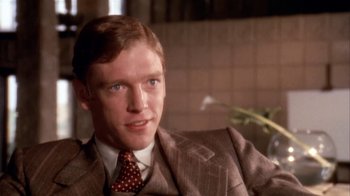 Movie still from “The Day of the Locust” (1975), directed by John Schlesinger – A man wearing a suit and tie in front of a wall; Close Up shot, Over the shoulder angle