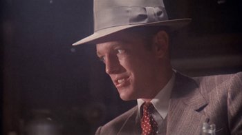 Movie still from “The Day of the Locust” (1975), directed by John Schlesinger – A person wearing a suit and a hat; Close Up shot, Over the shoulder angle