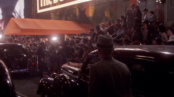 Movie still from “The Day of the Locust” (1975), directed by John Schlesinger – A crowd of people standing next to cars on a city street; Extreme Wide shot, High angle