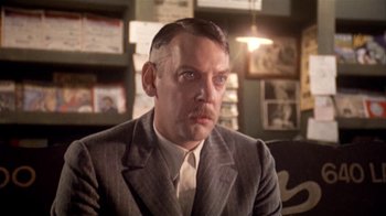 Movie still from “The Day of the Locust” (1975), directed by John Schlesinger – A man in a suit sitting in front of a window; Close Up shot, Low angle