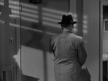 Movie still from “The Day the Earth Stood Still” (1951), directed by Robert Wise – A man in a suit and a hat standing in front of an open door; Medium shot, Over the shoulder angle