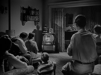 Movie still from “The Day the Earth Stood Still” (1951), directed by Robert Wise – A group of people sitting in front of a television; Wide shot, High angle