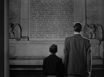 Movie still from “The Day the Earth Stood Still” (1951), directed by Robert Wise – Two people standing in front of a wall with a poem on it; Medium shot, Low angle