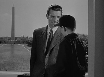 Movie still from “The Day the Earth Stood Still” (1951), directed by Robert Wise – A man standing next to another man wearing a baseball cap; Medium shot, Over the shoulder angle