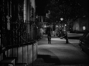 Movie still from “The Day the Earth Stood Still” (1951), directed by Robert Wise – A man riding a skateboard down the side of a sidewalk; Extreme Wide shot, High angle