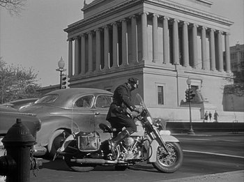 Movie still from “The Day the Earth Stood Still” (1951), directed by Robert Wise – A black and white photo of a man riding a motorcycle; Extreme Wide shot, Low angle