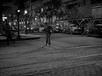 Movie still from “The Day the Earth Stood Still” (1951), directed by Robert Wise – A man riding a skate board down a street at night; Extreme Wide shot, High angle
