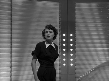 Movie still from “The Day the Earth Stood Still” (1951), directed by Robert Wise – A woman standing in front of a wall with lights on it; Medium shot, Low angle