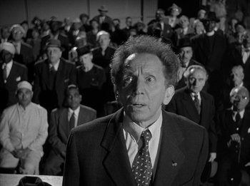 Movie still from “The Day the Earth Stood Still” (1951), directed by Robert Wise – An older man in a suit and tie in front of a crowd; Medium shot, Over the shoulder angle