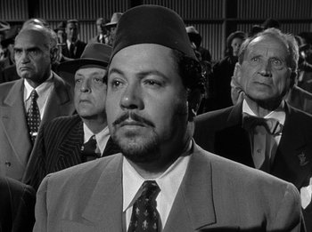 Movie still from “The Day the Earth Stood Still” (1951), directed by Robert Wise – A black and white photo of a man in a suit and hat; Medium shot, Over the shoulder angle