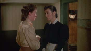 Movie still from “The Dead” (1987), directed by John Huston – Two young women are standing in a room talking; Medium shot, Over the shoulder angle