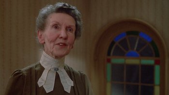 Movie still from “The Dead” (1987), directed by John Huston – An older woman wearing a dress and a bow tie; Close Up shot, Low angle