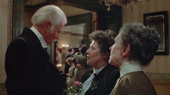 Movie still from “The Dead” (1987), directed by John Huston – A group of people gathered at a party; Medium shot, Over the shoulder angle