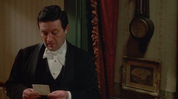 Movie still from “The Dead” (1987), directed by John Huston – A man in a tuxedo holding a piece of paper in his hands; Medium shot, High angle